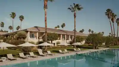 Clubhouse and resort-style pool of a Florida residential community with lounge chairs and palm trees