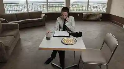 Real estate agent sitting alone at a table in an empty staged living room during a quiet open house
