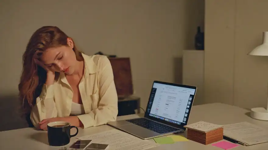 Agent doing evening admin work at a home office desk covered in notes